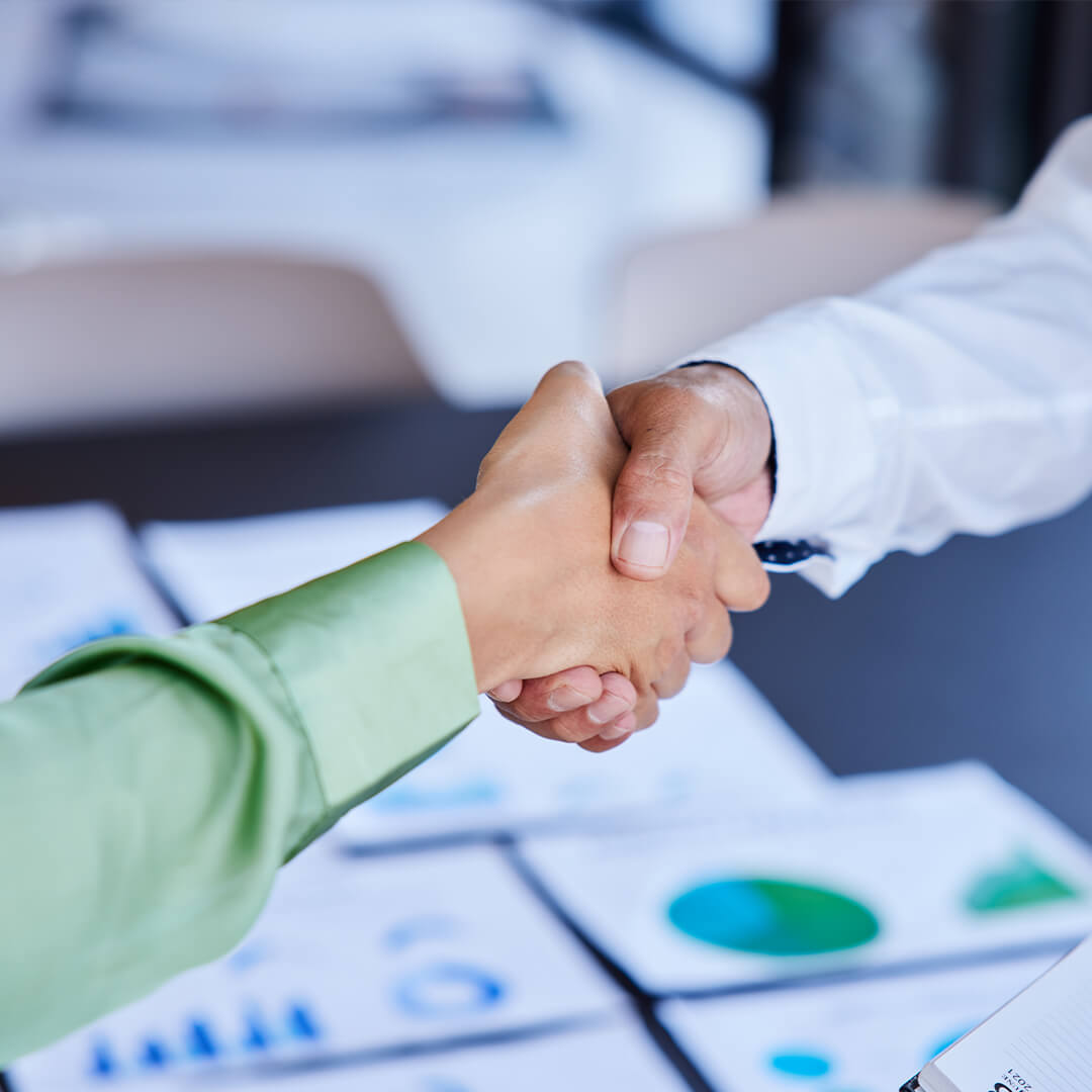 Handschlag über Unterlagen mit Diagrammen – Karriere bei NutraPet in Produktion, Entwicklung, Verwaltung und kaufmännischen Bereichen